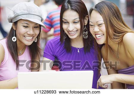 Stock Image - Close-up of three young women using a laptop. Fotosearch