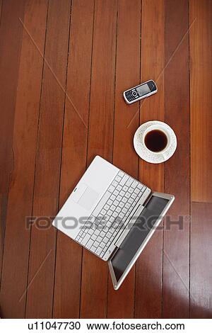 High angle view of a laptop and a mobile phone with a tea cup on a hardwood floor View Large Photo Image Stock Image - High angle view of a laptop and a mobile phone with a tea cup on a hardwood floor. Fotosearch