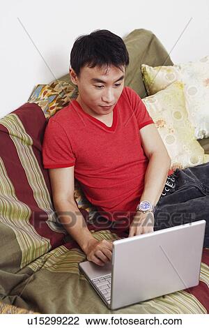 Stock Image - High angle view of a mid adult man using a laptop. Fotosearch