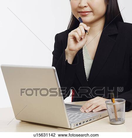 Stock Image - Portrait of a businesswoman sitting in front of a laptop. Fotosearch