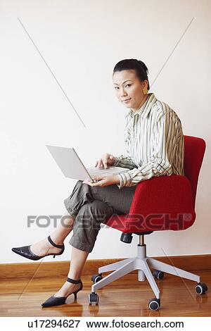 Stock Photo - Portrait of a businesswoman sitting in an armchair and using a laptop. Fotosearch