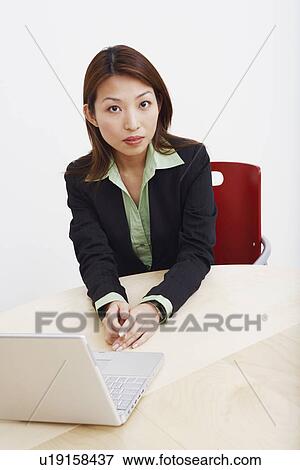 Stock Photo - Portrait of a businesswoman sitting with a laptop in a board room. Fotosearch