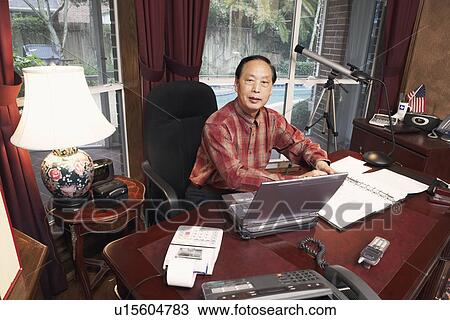 Stock Image - Portrait of a senior man sitting in front of a laptop. Fotosearch