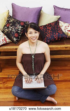 Portrait of a young woman smiling and using a laptop View Large Photo Image Stock Image - Portrait of a young woman smiling and using a laptop. Fotosearch