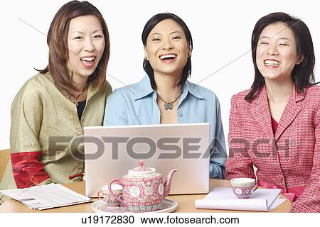 Portrait of three businesswomen in front of a laptop View Large Photo Image Stock Image - Portrait of three businesswomen in front of a laptop. Fotosearch