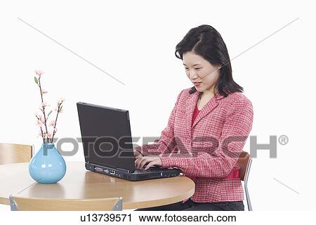 Stock Image - Side profile of a businesswoman using a laptop. Fotosearch