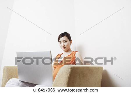 Stock Photograph - Side profile of a young woman using a laptop. Fotosearch