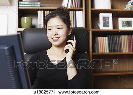Close-up of a businesswoman sitting in front of a computer monitor using a mobile phone View Large Photo Image Stock Image - Close-up of a businesswoman sitting in front of a computer monitor using a mobile phone. Fotosearch