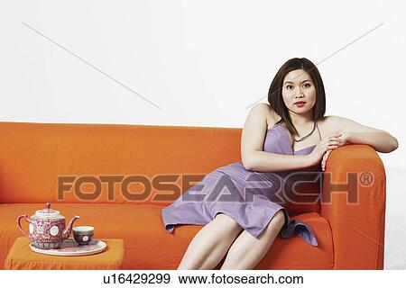 Stock Photo - Close-up of a young woman sitting on a couch. Fotosearch