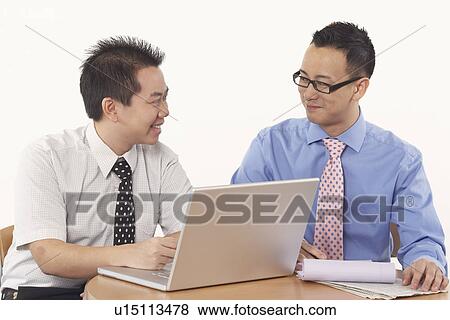Close-up of two businessmen sitting in front of a laptop View Large Photo Image Stock Photo - Close-up of two businessmen sitting in front of a laptop. Fotosearch