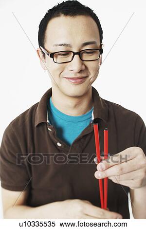 Portrait of a young man holding chopsticks View Large Photo Image Stock Photography - Portrait of a young man holding chopsticks. Fotosearch