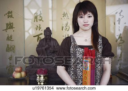 Picture - Portrait of a young woman holding a box of incense sticks. Fotosearch