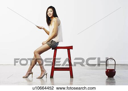 Stock Image - Portrait of a young woman holding a mobile phone. Fotosearch