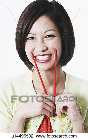 Portrait of a young woman holding chopsticks View Large Photo Image Stock Image - Portrait of a young woman holding chopsticks. Fotosearch