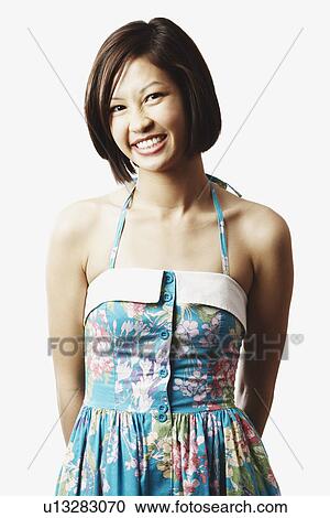 Portrait of a young woman standing with her hands behind her back View Large Photo Image Stock Image - Portrait of a young woman standing with her hands behind her back. Fotosearch