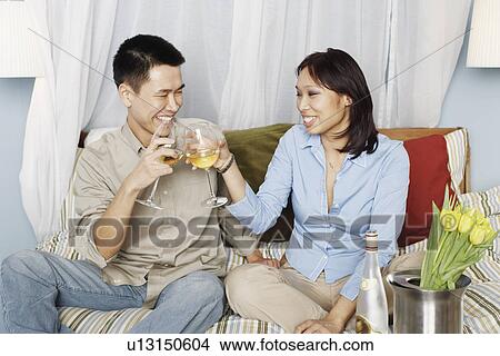 Young couple sitting on the bed toasting with wineglasses View Large Photo Image Picture - Young couple sitting on the bed toasting with wineglasses. Fotosearch