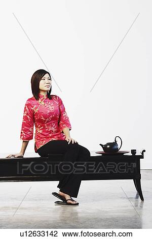 Young woman sitting on a table View Large Photo Image Stock Image - Young woman sitting on a table. Fotosearch