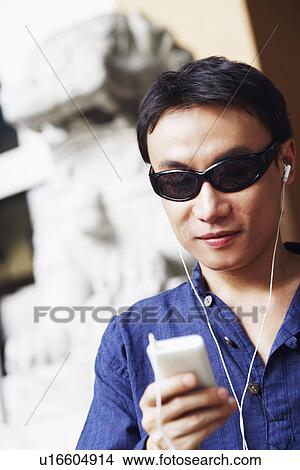 Close-up of a mid adult man listening to an MP3 player View Large Photo Image Picture - Close-up of a mid adult man listening to an MP3 player. Fotosearch