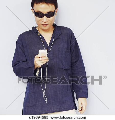 Close-up of a mid adult man listening to an MP3 player View Large Photo Image Stock Photography - Close-up of a mid adult man listening to an MP3 player. Fotosearch