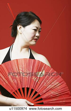 Close-up of a mid adult woman holding a folding fan View Large Photo Image Picture - Close-up of a mid adult woman holding a folding fan. Fotosearch