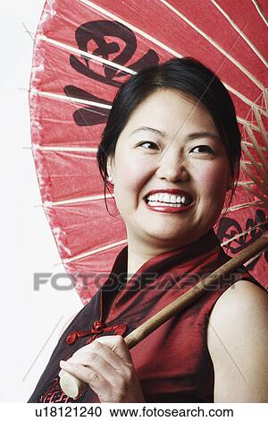 Stock Image - Close-up of a mid adult woman holding a parasol. Fotosearch