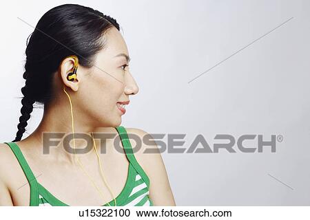 Stock Image - Close-up of a mid adult woman wearing headphones and listening to music. Fotosearch