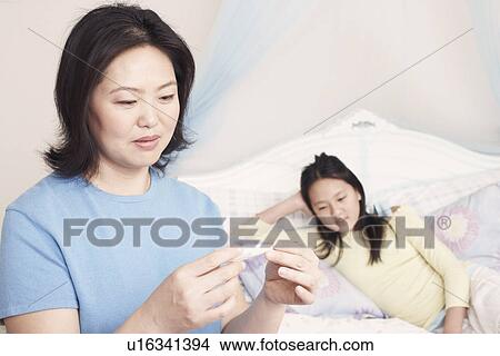 Close-up of a mother checking her daughter's temperature View Large Photo Image Picture - Close-up of a mother checking her daughter's temperature. Fotosearch