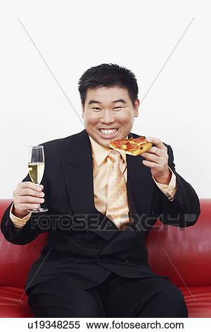 Portrait of a businessman sitting on a couch and holding a slice of pizza with a champagne flute View Large Photo Image Stock Photography - Portrait of a businessman sitting on a couch and holding a slice of pizza with a champagne flute. Fotosearch