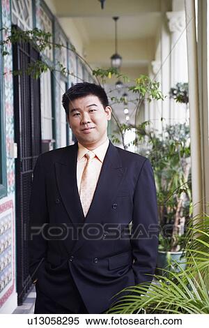 Stock Photography - Portrait of a businessman standing in the corridor and smirking. Fotosearch