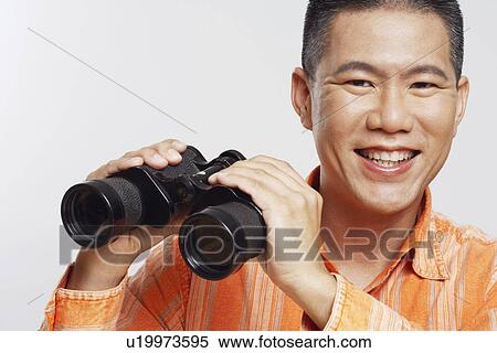 Portrait of a mid adult man holding a pair of binoculars and smiling View Large Photo Image Stock Photography - Portrait of a mid adult man holding a pair of binoculars and smiling. Fotosearch