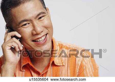 Picture - Portrait of a mid adult man talking on a mobile phone and smiling. Fotosearch