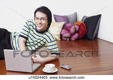 Stock Image - Portrait of a mid adult man using a laptop and smiling. Fotosearch