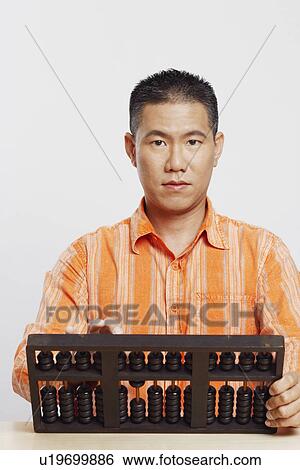 Stock Photograph - Portrait of a mid adult man using an abacus. Fotosearch