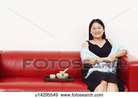 Stock Photo - Portrait of a mid adult woman sitting on a couch and smiling. Fotosearch