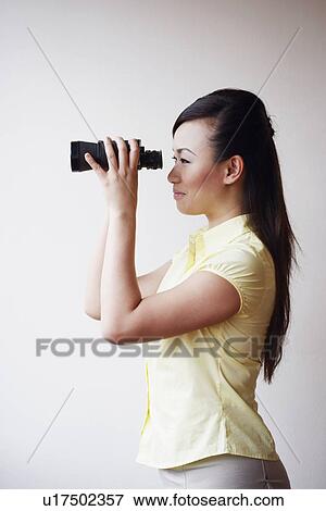 Side profile of a mid adult woman looking through a pair of binoculars View Large Photo Image Stock Photo - Side profile of a mid adult woman looking through a pair of binoculars. Fotosearch