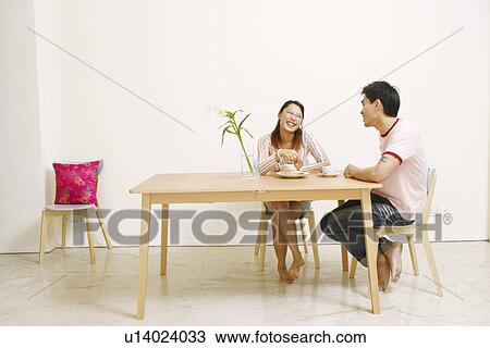 Stock Image - Young woman and a mid adult man looking at each other. Fotosearch