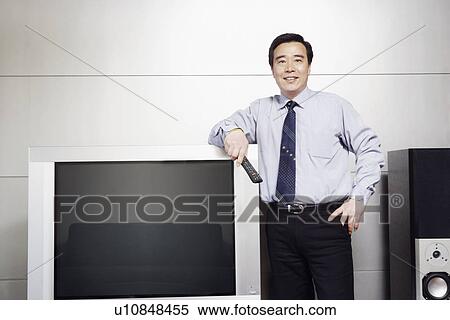 Businessman standing beside a television smiling View Large Photo Image Stock Photography - Businessman standing beside a television smiling. Fotosearch