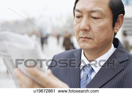 Stock Image - Close-up of a businessman reading a newspaper. Fotosearch