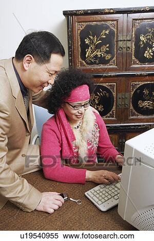 Stock Photography - Close-up of a businesswoman using a computer with a businessman sitting beside her. Fotosearch