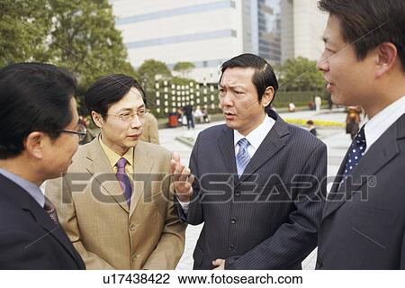 Stock Image - Close-up of four businessmen talking to each other. Fotosearch