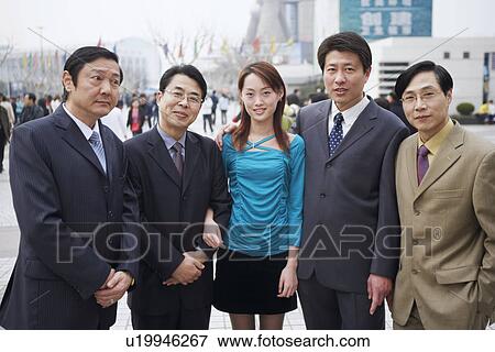 Stock Photo - Four businessmen standing with a young woman. Fotosearch