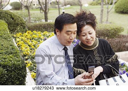 Mature couple looking at a mobile phone smiling View Large Photo Image Stock Image - Mature couple looking at a mobile phone smiling. Fotosearch