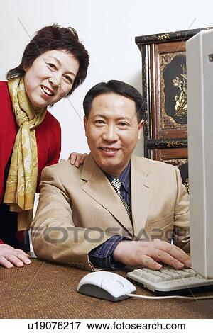 Stock Photo - Portrait of a businessman using a computer with a businesswoman standing behind him. Fotosearch