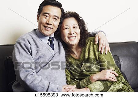 Portrait of a mature couple sitting together on a couch smiling View Large Photo Image Stock Image - Portrait of a mature couple sitting together on a couch smiling. Fotosearch