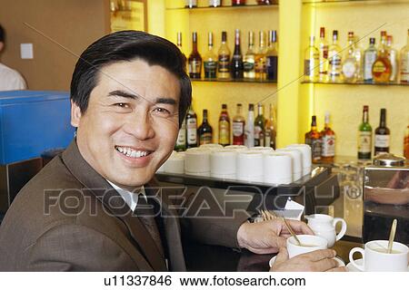 Portrait of a mature man holding a cup of coffee in a restaurant View Large Photo Image Stock Photograph - Portrait of a mature man holding a cup of coffee in a restaurant. Fotosearch