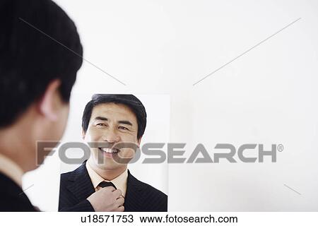 Rear view of a businessman looking into a mirror adjusting his tie View Large Photo Image Stock Image - Rear view of a businessman looking into a mirror adjusting his tie. Fotosearch