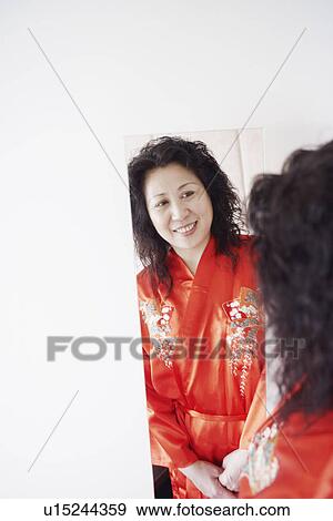 Rear view of a mature woman looking into a mirror smiling View Large Photo Image Stock Photo - Rear view of a mature woman looking into a mirror smiling. Fotosearch