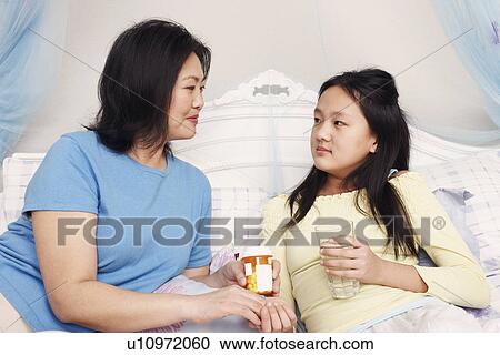 Stock Image - Close-up of a mother giving her daughter medicine. Fotosearch