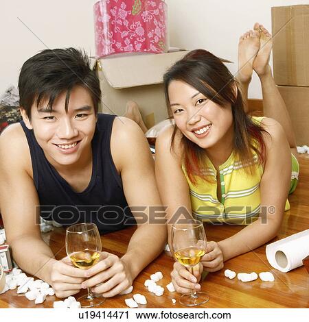 Portrait of a young couple lying on the floor and holding glasses of wine View Large Photo Image Stock Image - Portrait of a young couple lying on the floor and holding glasses of wine. Fotosearch