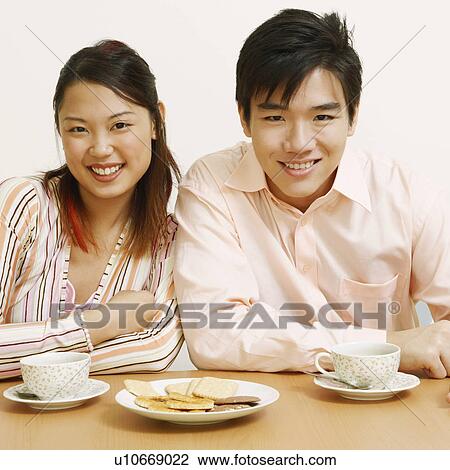 Portrait of a young couple sitting together and smiling View Large Photo Image Stock Image - Portrait of a young couple sitting together and smiling. Fotosearch